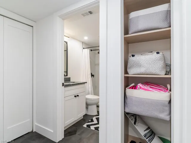 Bathroom featuring a shower with curtain, toilet, vanity, and visible vents