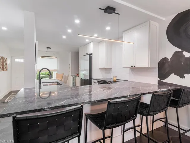 Kitchen with a sink, tasteful backsplash, a peninsula, built in refrigerator, and white cabinets