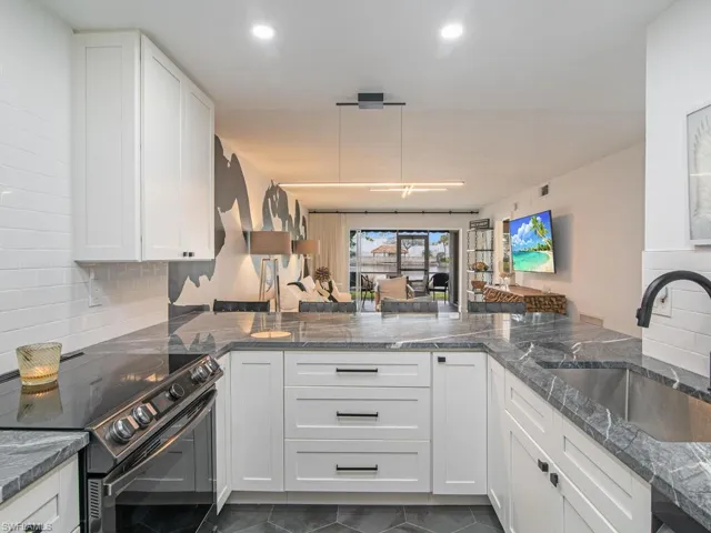 Kitchen with a sink, black range with electric stovetop, white cabinetry, dark tile patterned floors, and decorative backsplash