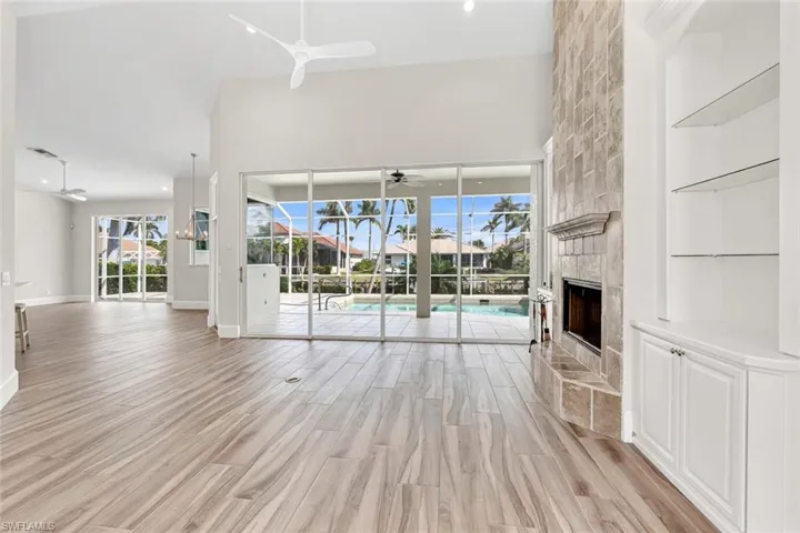 Unfurnished living room featuring ceiling fan, light hardwood / wood-style flooring, and a towering ceiling