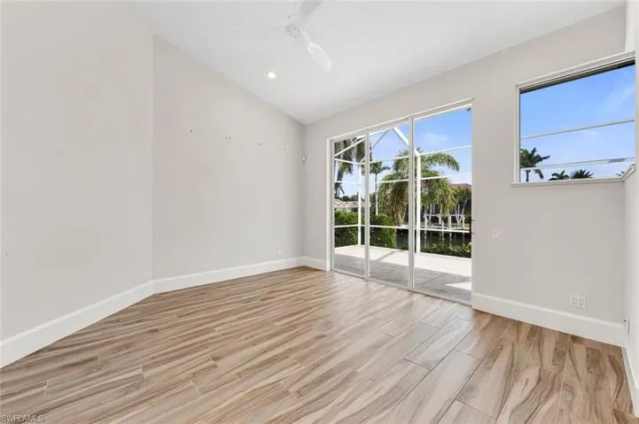 Spare room with vaulted ceiling, ceiling fan, plenty of natural light, and light wood-type flooring