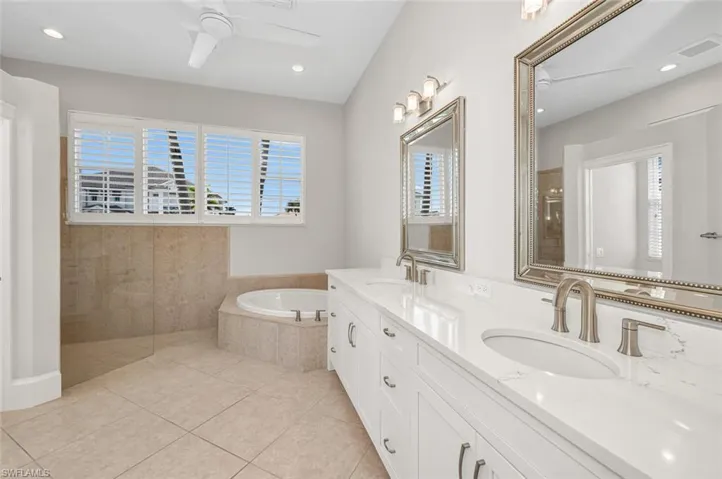 Bathroom with ceiling fan, tile patterned floors, shower with separate bathtub, and vanity