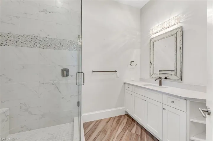Bathroom with hardwood / wood-style flooring, vanity, and an enclosed shower