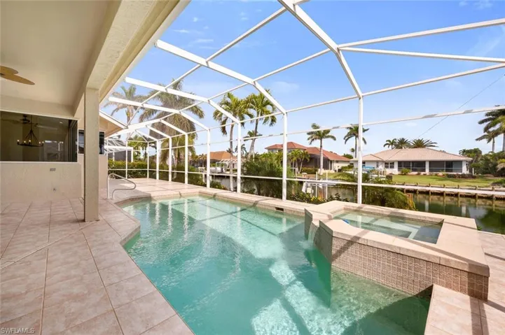 View of swimming pool with a water view, a patio, an in ground hot tub, and glass enclosure