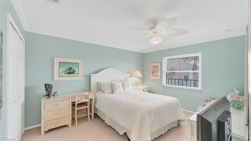 Carpeted 2nd bedroom featuring crown molding, a closet, ceiling fan, and a desk