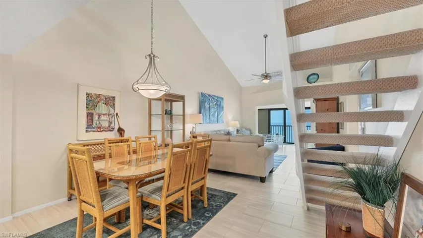 Dining area with high vaulted ceiling, a ceiling fan, and light.