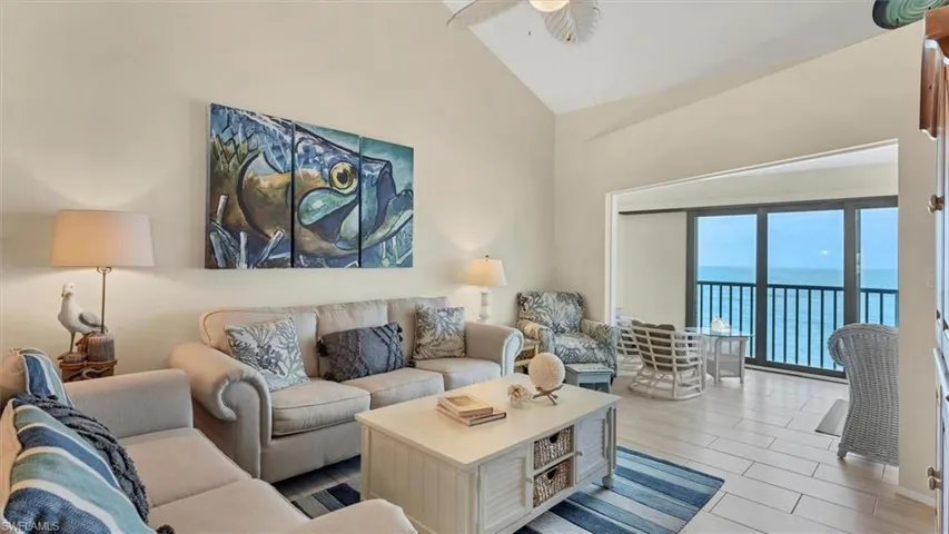Living room featuring a water view, ceiling fan, and high vaulted ceiling