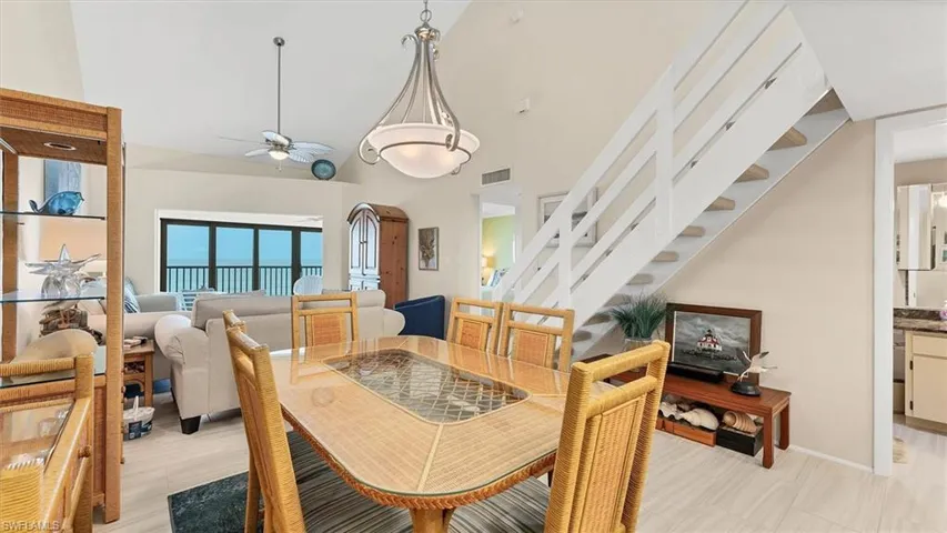 Dining room featuring stairs, ceiling fan, and high vaulted ceiling