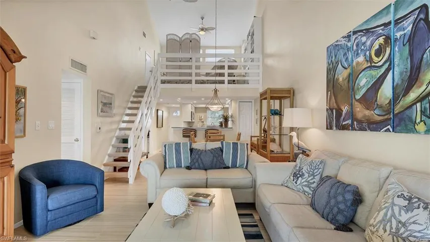 Living area featuring a towering ceiling, a ceiling fan and stairway to loft.