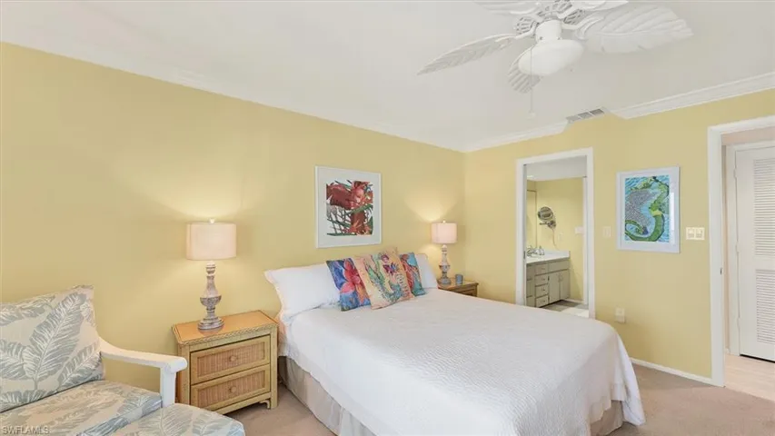 Bedroom with a ceiling fan, light carpet, connected bathroom, and ornamental molding
