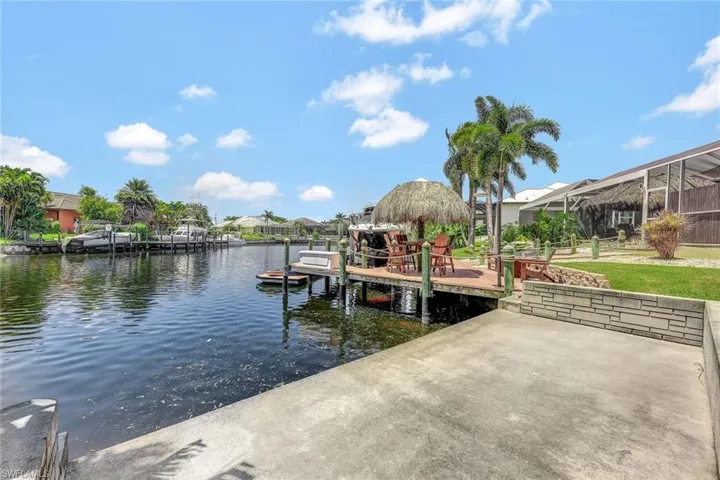 View of dock with a lawn and a water view