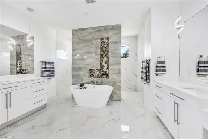 Bathroom with a tub, tile walls, vanity, and tile patterned floors