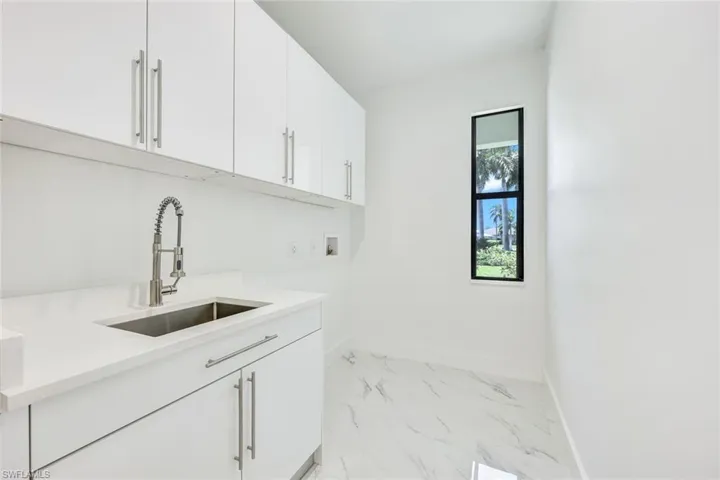 Laundry area with sink, cabinets, hookup for a washing machine, and light tile patterned floors