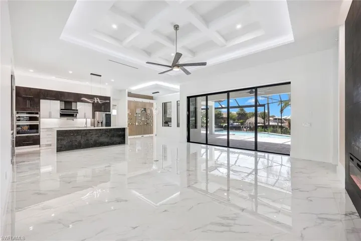 Unfurnished living room featuring beam ceiling, ceiling fan, light tile patterned flooring, and coffered ceiling