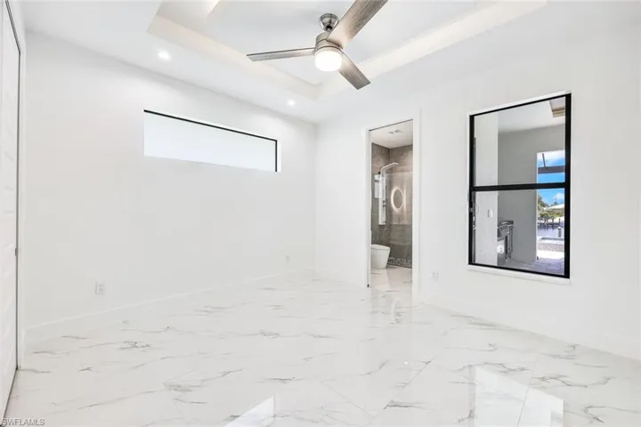 Empty room featuring ceiling fan, a raised ceiling, and light tile patterned floors