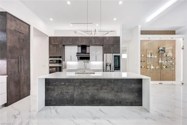 Kitchen featuring a kitchen island with sink, appliances with stainless steel finishes, sink, and light tile patterned floors
