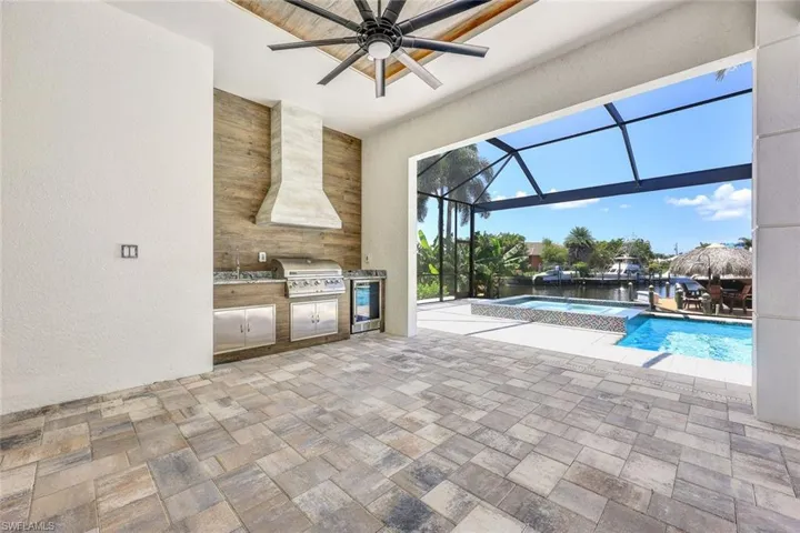 View of pool featuring exterior kitchen, a lanai, a patio, a grill, and ceiling fan