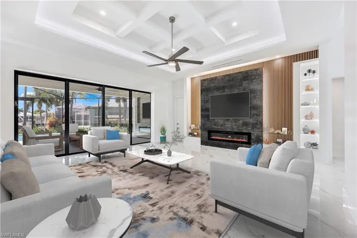 Living room featuring a high end fireplace, coffered ceiling, beam ceiling, and ceiling fan