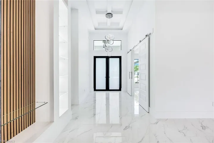 Tiled foyer with a towering ceiling and a barn door