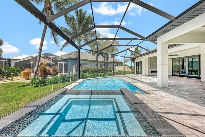 View of swimming pool with ceiling fan, an in ground hot tub, glass enclosure, a patio area, and a yard