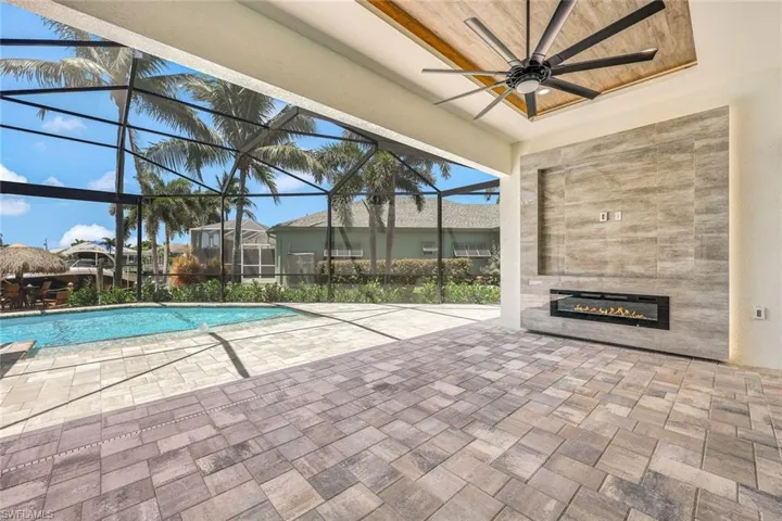View of pool with glass enclosure, a patio, and ceiling fan