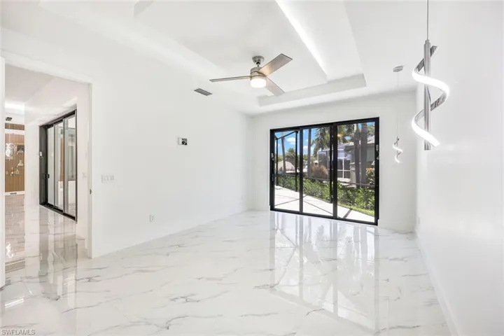 Tiled spare room featuring ceiling fan and a tray ceiling