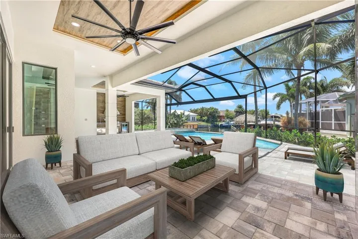 View of patio with an outdoor hangout area, glass enclosure, and ceiling fan