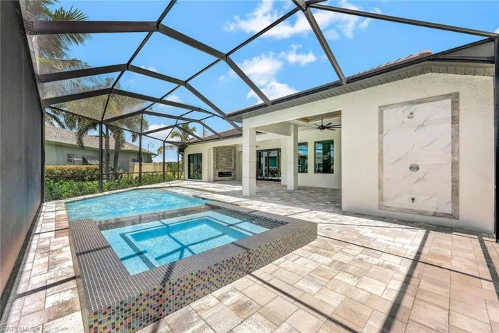 View of pool with ceiling fan, a lanai, an in ground hot tub, and a patio