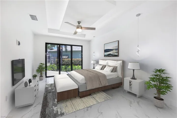 Bedroom with access to exterior, ceiling fan, and a tray ceiling