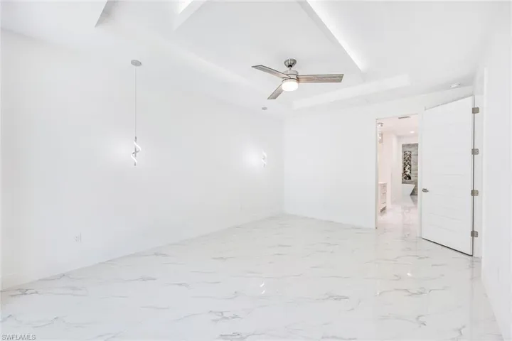 Tiled empty room featuring a tray ceiling and ceiling fan