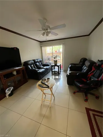Living room featuring crown molding, ceiling fan, and light tile patterned floors