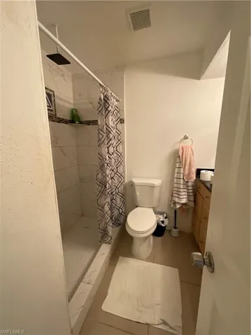 Bathroom featuring vanity, a shower with curtain, toilet, and tile patterned flooring