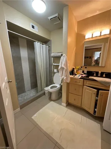 Bathroom featuring vanity, tile patterned floors, walk in shower, and toilet