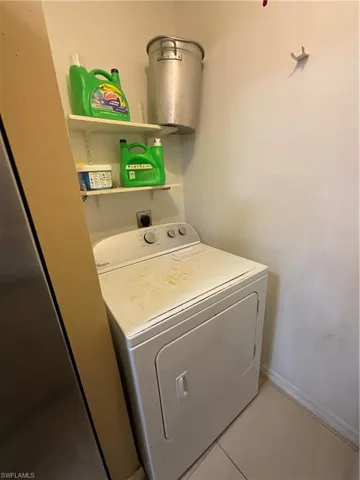 Clothes washing area with washer / clothes dryer and light tile patterned floors