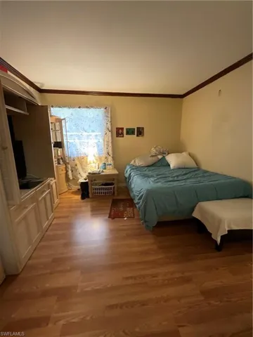 Bedroom with wood-type flooring and ornamental molding