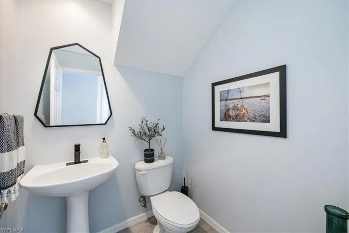 Bathroom featuring lofted ceiling, wood-type flooring, and toilet