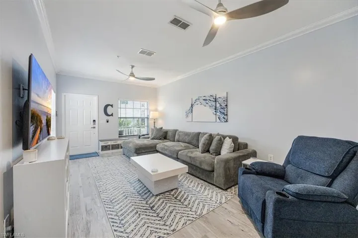 Living room with crown molding, light wood-type flooring, and ceiling fan