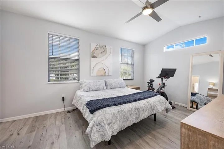 Bedroom featuring ceiling fan, lofted ceiling, multiple windows, and light hardwood / wood-style floors