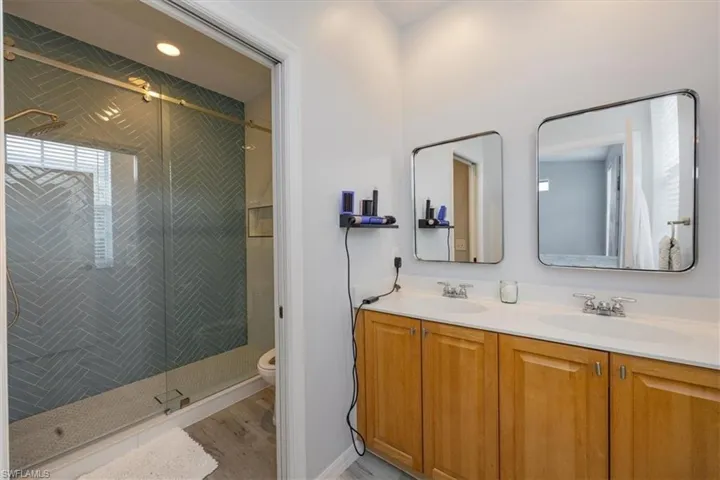 Bathroom with vanity, toilet, hardwood / wood-style flooring, and a shower with shower door