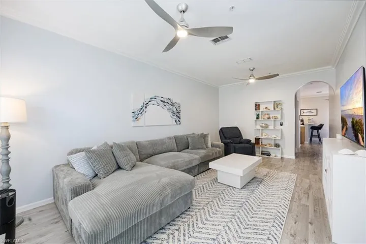 Living room with ornamental molding, light hardwood / wood-style floors, and ceiling fan
