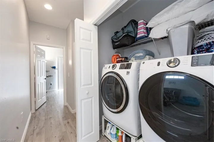Laundry area with light hardwood / wood-style flooring and washing machine and clothes dryer