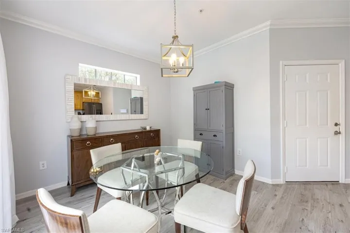 Dining space with ornamental molding, light hardwood / wood-style flooring, and a notable chandelier