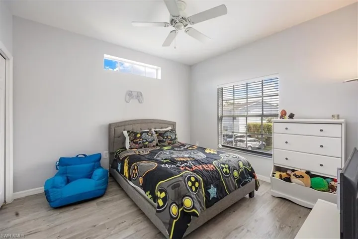 Bedroom with ceiling fan, multiple windows, and light wood-type flooring