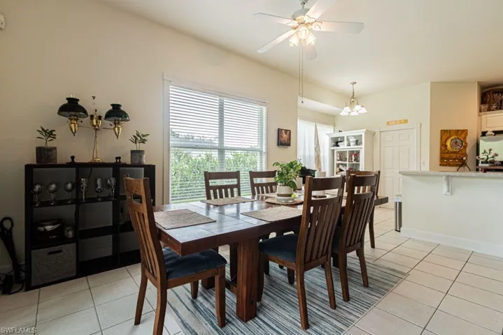 Dining area featuring light tile patterned floors, ceiling fan, and a chandelier