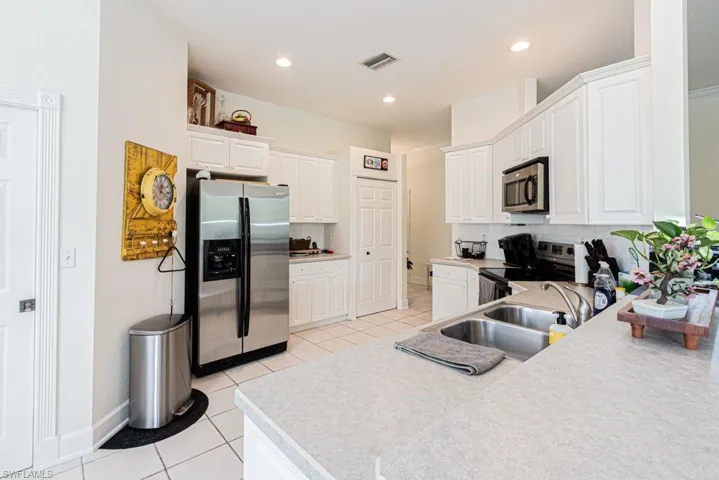 Kitchen featuring stainless steel appliances, light tile patterned floors, white cabinetry, backsplash, and recessed lighting