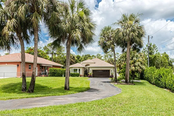 Ranch-style home featuring stucco siding, an attached garage, a front lawn, and driveway
