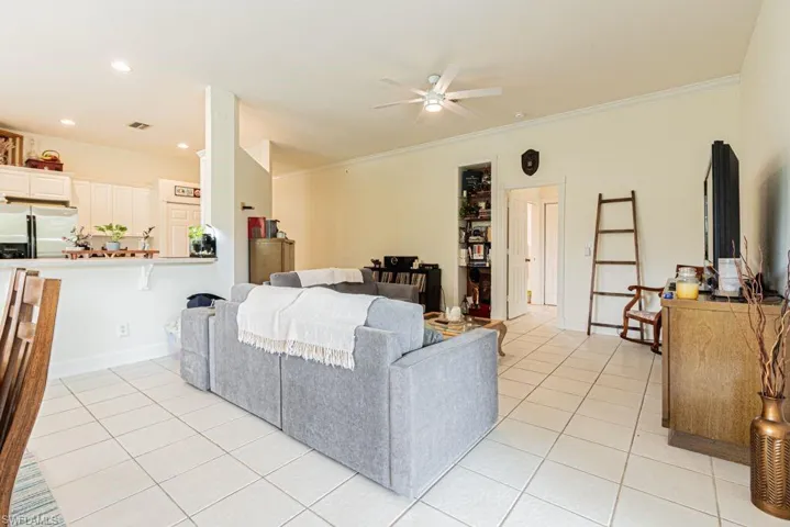 Living area featuring light tile patterned floors, ceiling fan, crown molding, and recessed lighting