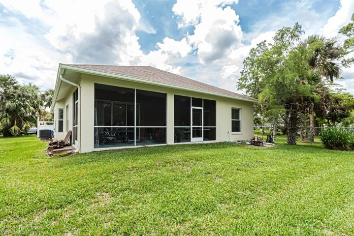 Back of property with stucco siding, a sunroom, and a fire pit