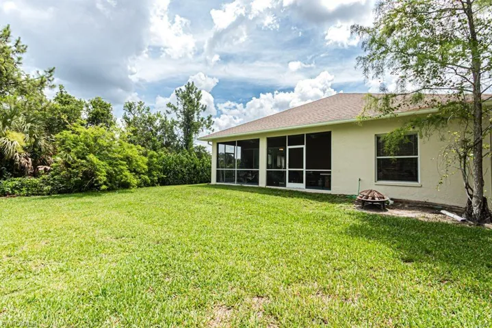 View of grassy yard featuring an outdoor fire pit and a sunroom