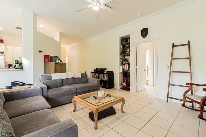 Living room with ceiling fan, light tile patterned floors, ornamental molding, and recessed lighting